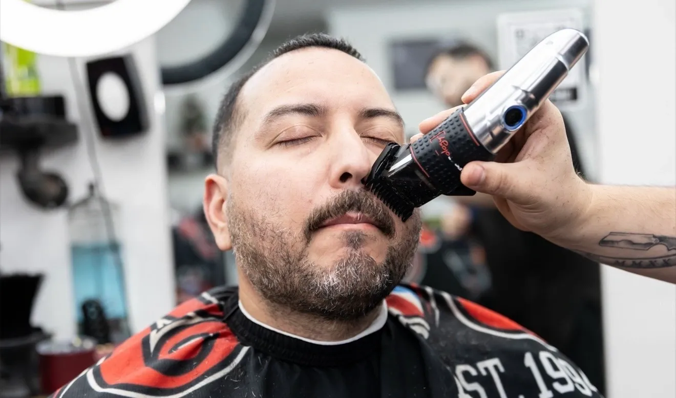 Man getting beard trimmed at barbershop.