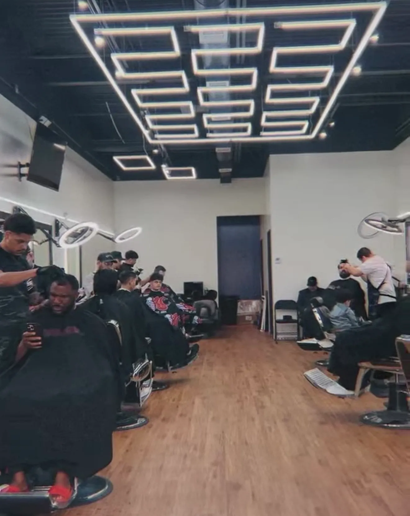 Barbershop with customers getting haircuts and styling.